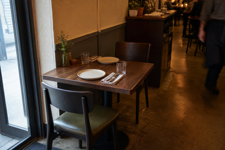 An empty restaurant table beside the entrance and a busy service passage