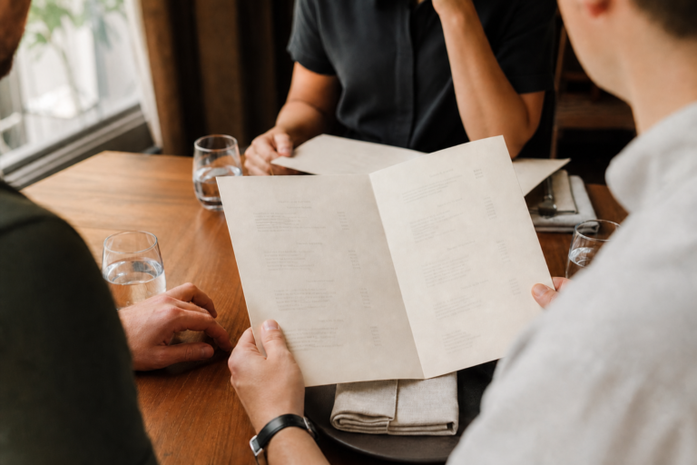Diners pause over restaurant menus before ordering